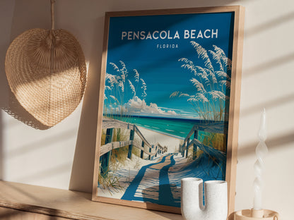 A framed poster of Pensacola Beach, Florida, featuring a coastal walkway with sea oats and blue ocean, is displayed on a wooden shelf next to a wicker decoration.