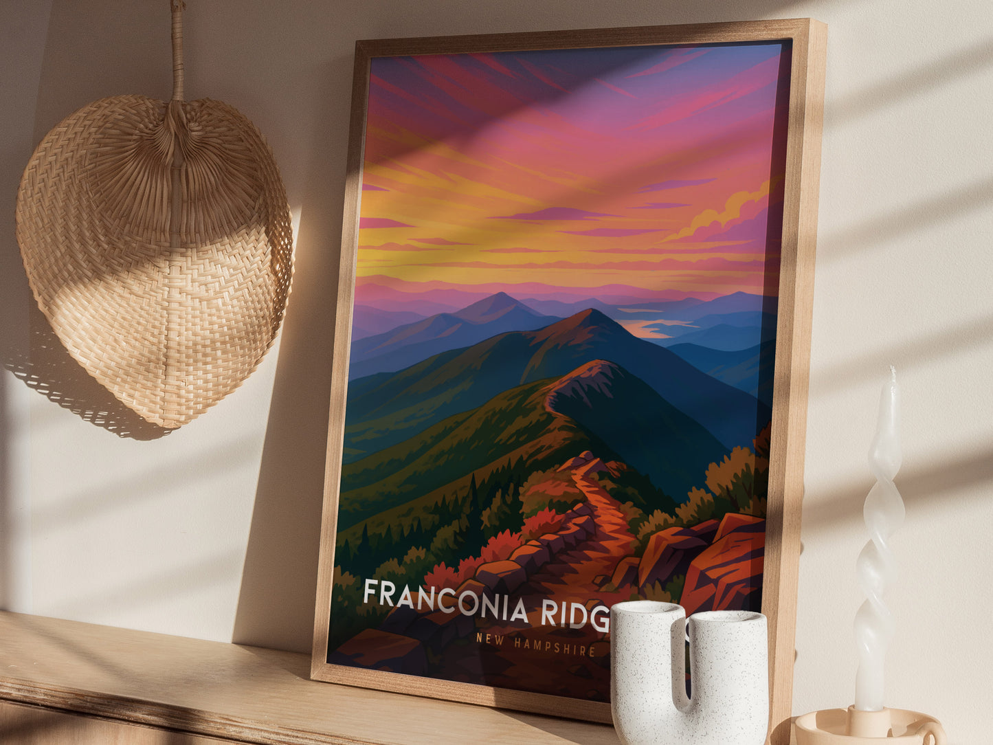 A colorful art print featuring a scenic view of Franconia Ridge in New Hampshire, showcasing vibrant pink and orange skies above rolling mountains and a winding trail.