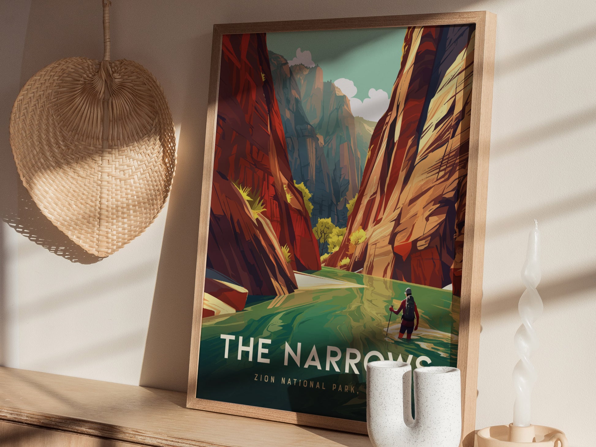 A framed poster of The Narrows at Zion National Park with vibrant canyon walls and a hiker in the river, displayed on a wooden shelf beside a wicker basket and.