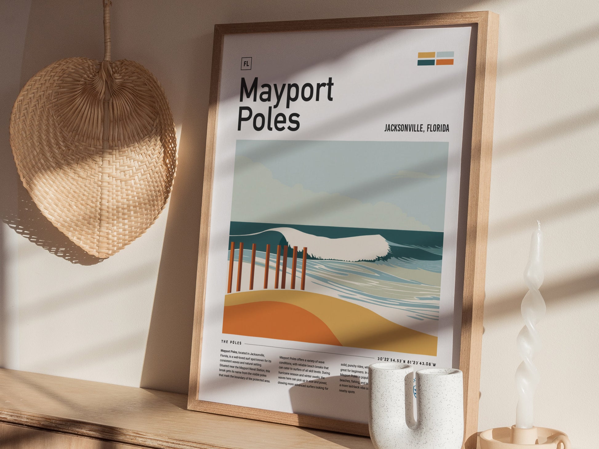 A framed Mayport Poles poster depicting a stylized beach scene with waves and poles is displayed on a wooden shelf. Nearby, a woven wall decoration and a twisted candle add.