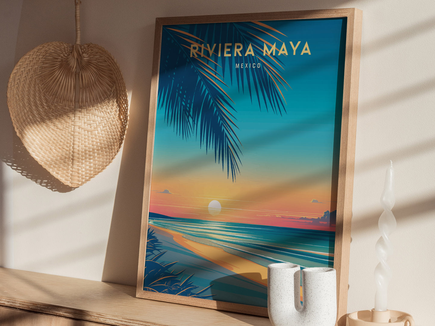 A framed poster titled Riviera Maya Mexico displays a vibrant beach scene with palm leaves, a setting sun,.