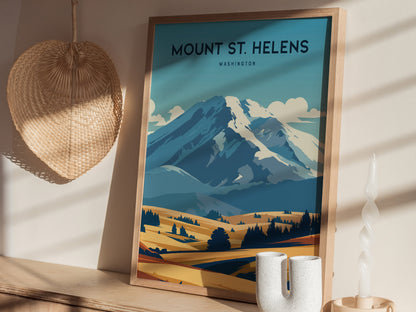 Framed Mount St. Helens poster with a stylized blue and yellow landscape, placed on a wooden shelf beside a woven wall decor and a twisted white candle.