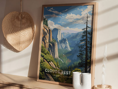 A framed Clouds Rest Trail poster depicting a scenic mountain landscape is displayed on a wooden surface alongside a wicker basket and a uniquely shaped white candle.