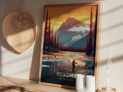 A framed Glacier National Park poster showcases a vibrant mountain landscape with a figure near a reflective lake. It sits on a shelf beside a woven basket and decorative candle.