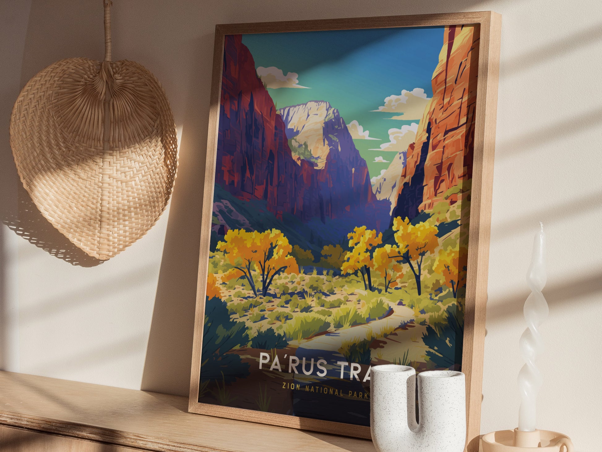 A framed poster of Zion National Parks Parus Trail featuring a vibrant landscape with red cliffs and yellow trees, displayed on a wooden shelf alongside a woven basket and a.
