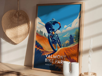 A framed poster of a mountain biker on a trail is displayed on a sunlit shelf, accompanied by a woven basket and a white ceramic vase.