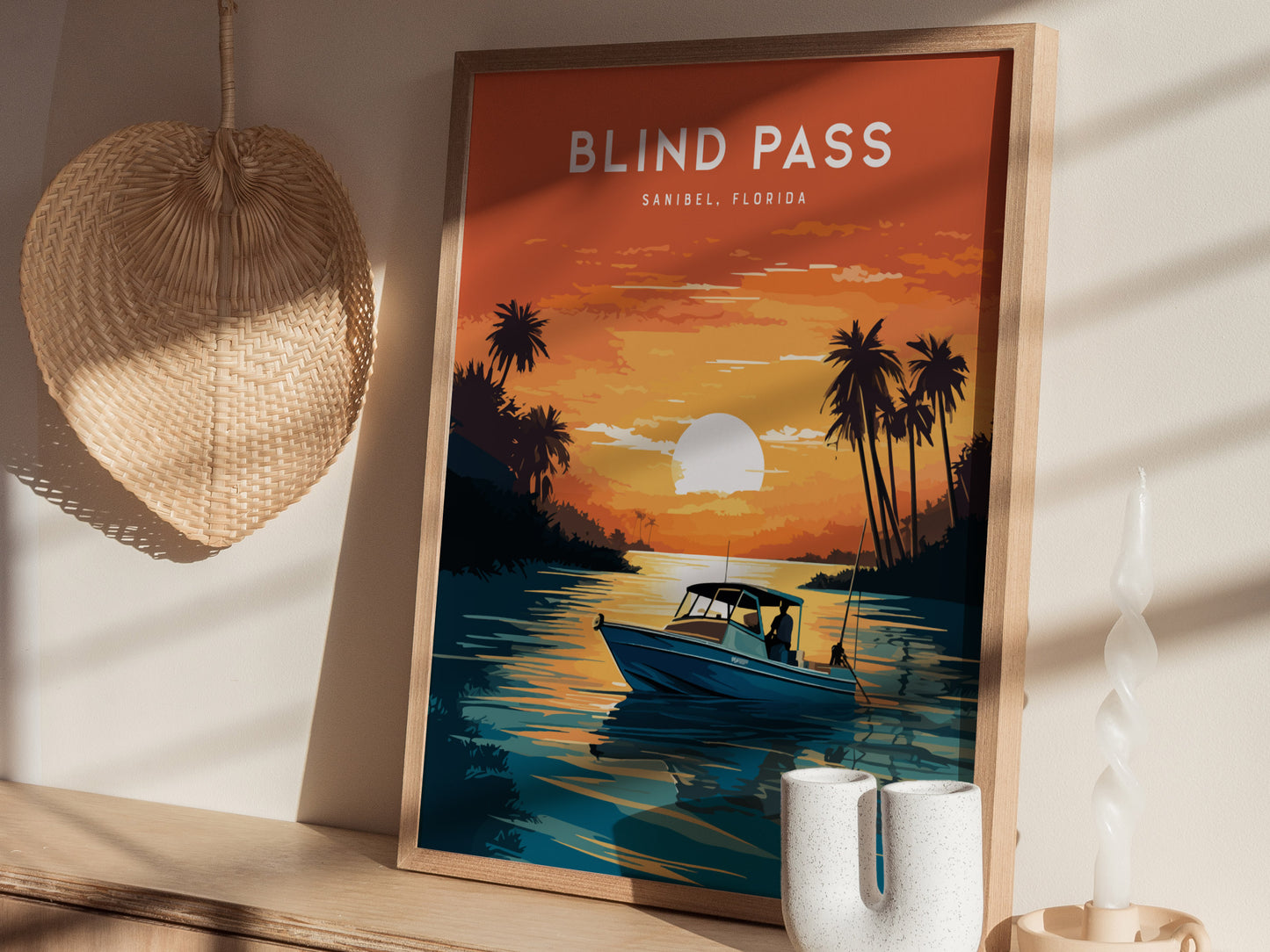 A framed poster titled Blind Pass, Sanibel, Florida depicts a lone fisherman in a boat at sunset, with palm trees silhouetted against an orange sky.