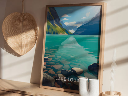 A framed Lake Louise poster with turquoise water and mountains is displayed on a wooden surface, alongside a woven basket and a unique white candle.