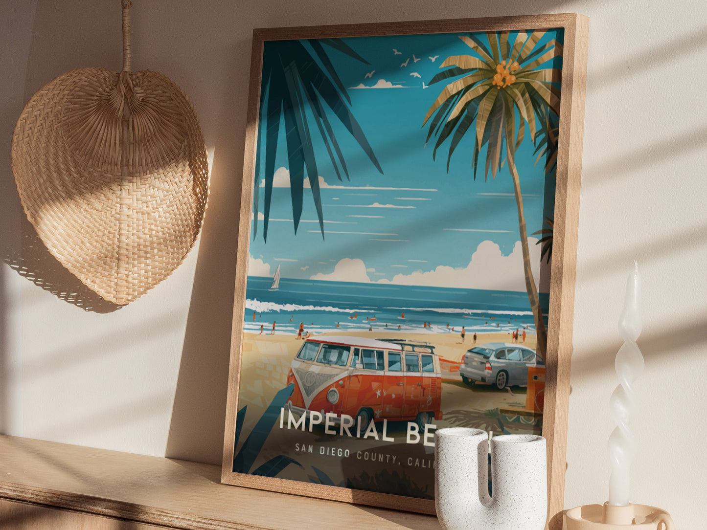 A framed poster of Imperial Beach, featuring palm trees, a vintage van, and a sandy coastline, is displayed on a shelf. A woven basket and candle are nearby.