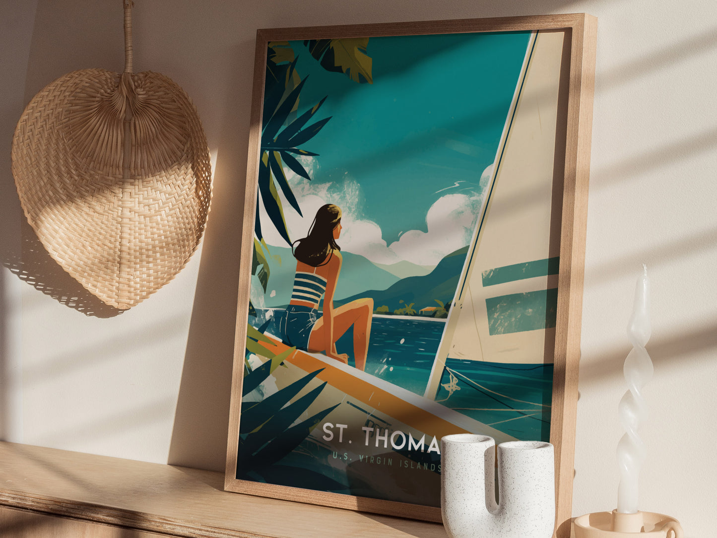 A framed St. Thomas travel poster with a woman on a sailboat is displayed on a shelf, accompanied by a woven wall decor and a decorative candle.