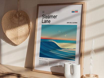 Framed Steamer Lane poster featuring a vibrant surf scene with waves and seagulls, placed on a wooden shelf beside a woven basket and a twisted white candle.