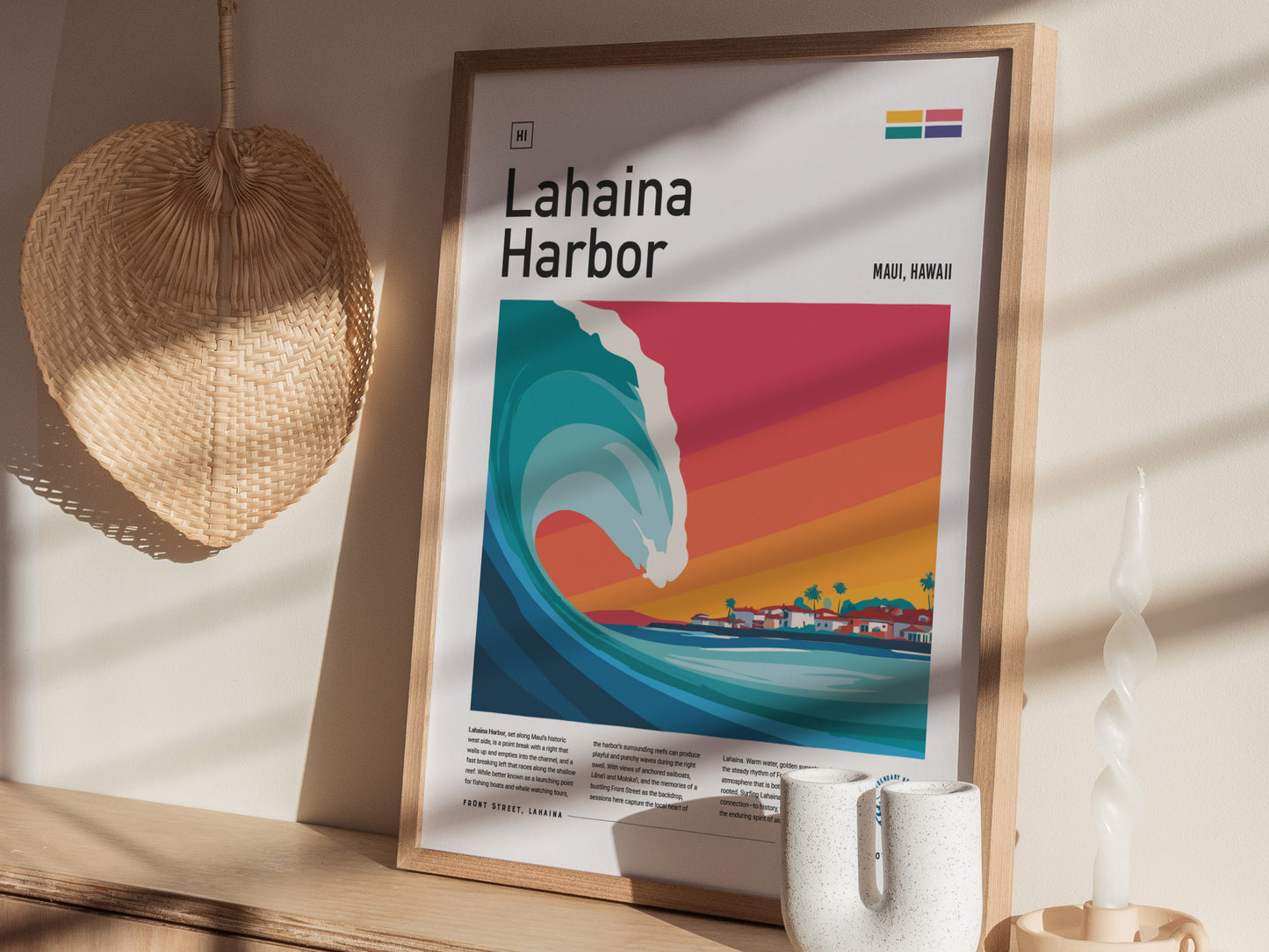 A framed poster titled Lahaina Harbor depicts a vibrant, stylized wave crashing toward a colorful sunset backdrop, with a coastal scene of Maui in the distance.