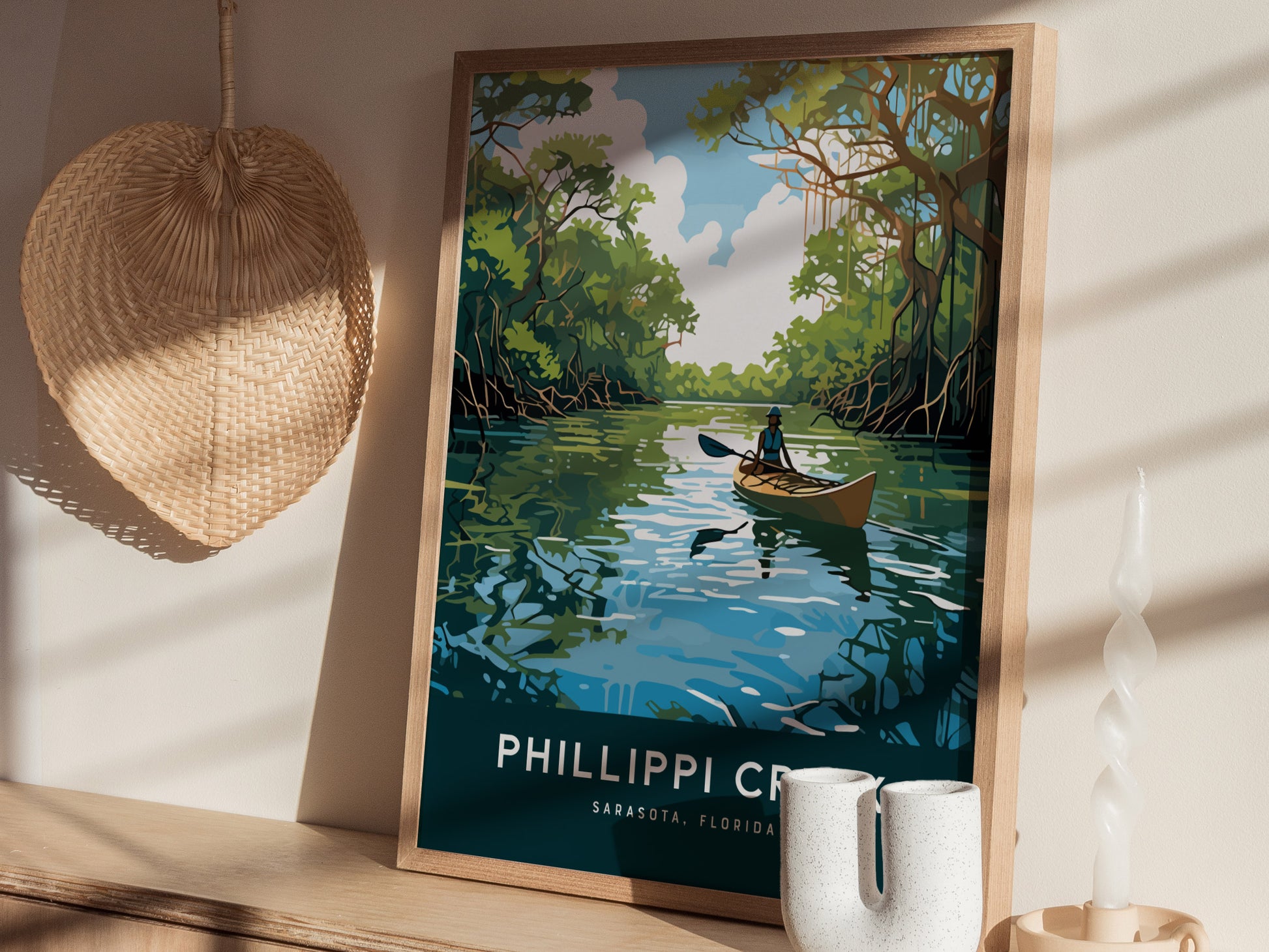 A framed poster of a kayaker on a serene waterway is displayed on a wooden shelf, accompanied by decorative items like a woven fan and a twisted candle.