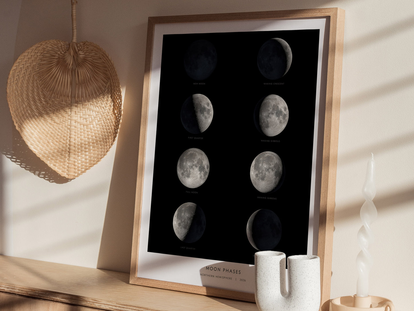 A framed poster displaying the eight phases of the Moon against a dark background, including new moon, waxing crescent, first quarter, waxing gibbous, full moon, waning gibbous, last quarter, and waning crescent.
