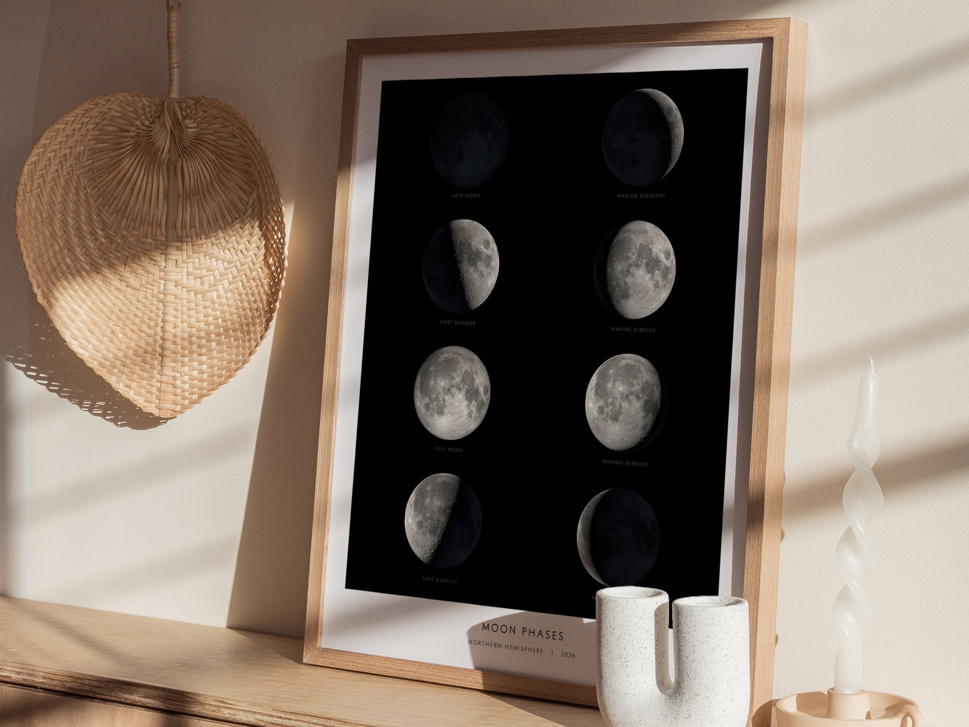 A framed poster displaying the eight phases of the Moon against a dark background, including new moon, waxing crescent, first quarter, waxing gibbous, full moon, waning gibbous, last quarter, and waning crescent.
