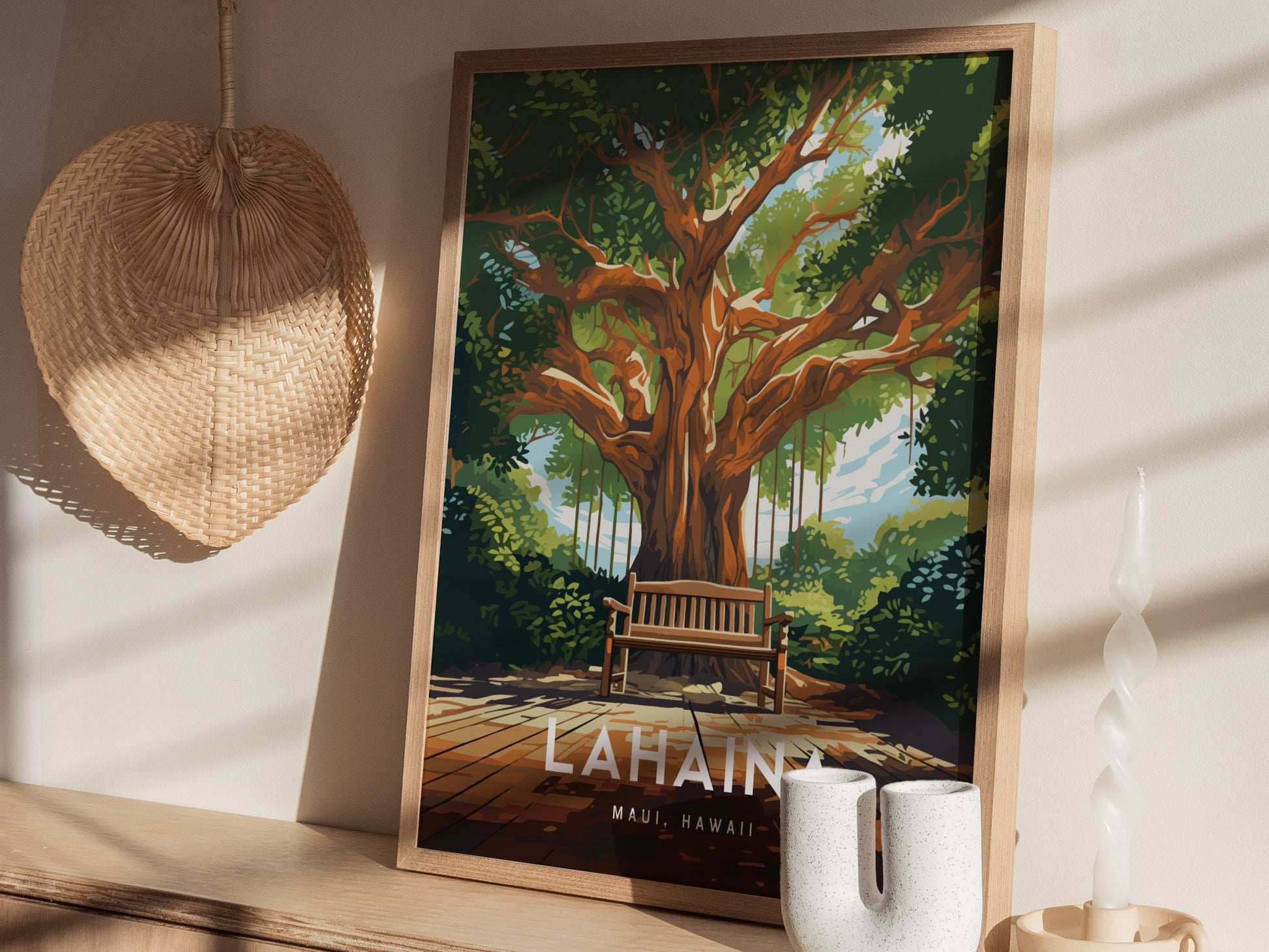 A framed poster of a lush banyan tree with a bench sits on a wooden shelf, accompanied by a woven hat and a twisted white candle.