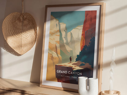 A framed Grand Canyon National Park poster with a minimalist design is displayed on a wooden surface, alongside a woven basket and a twisted candle.