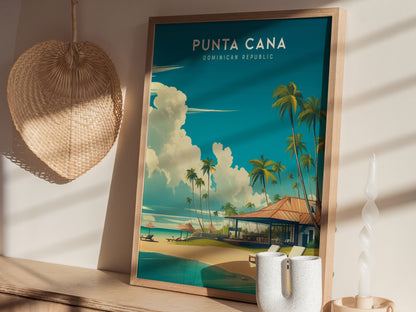 A framed Punta Cana poster depicting a serene beach scene with palm trees and a vibrant sky is displayed on a wooden surface. Adjacent to it is a woven wall decoration and a uniquely shaped white candle.