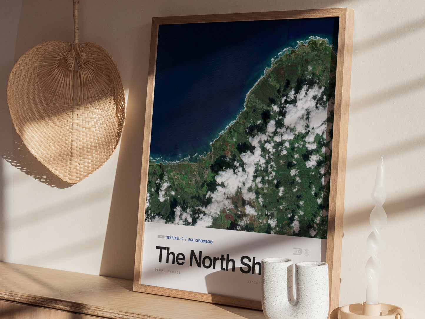 A beautifully framed aerial poster titled The North Shore showcases a vibrant satellite view of lush green land and deep blue ocean waters, accented by patches of white clouds.