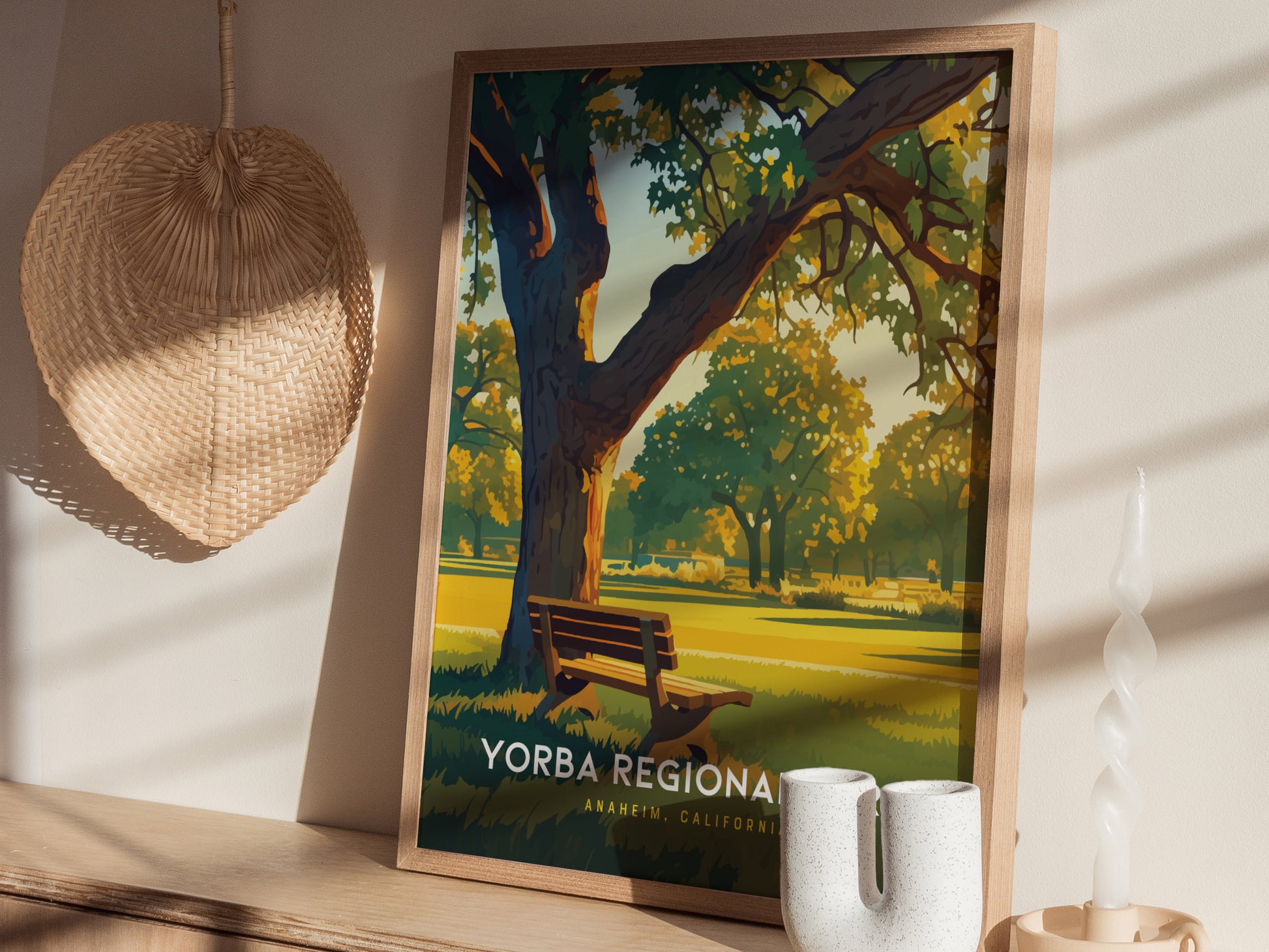 A framed Yorba Regional Park poster is displayed on a shelf, depicting a scenic park with a tree and bench. A woven basket and decorative candle are nearby.