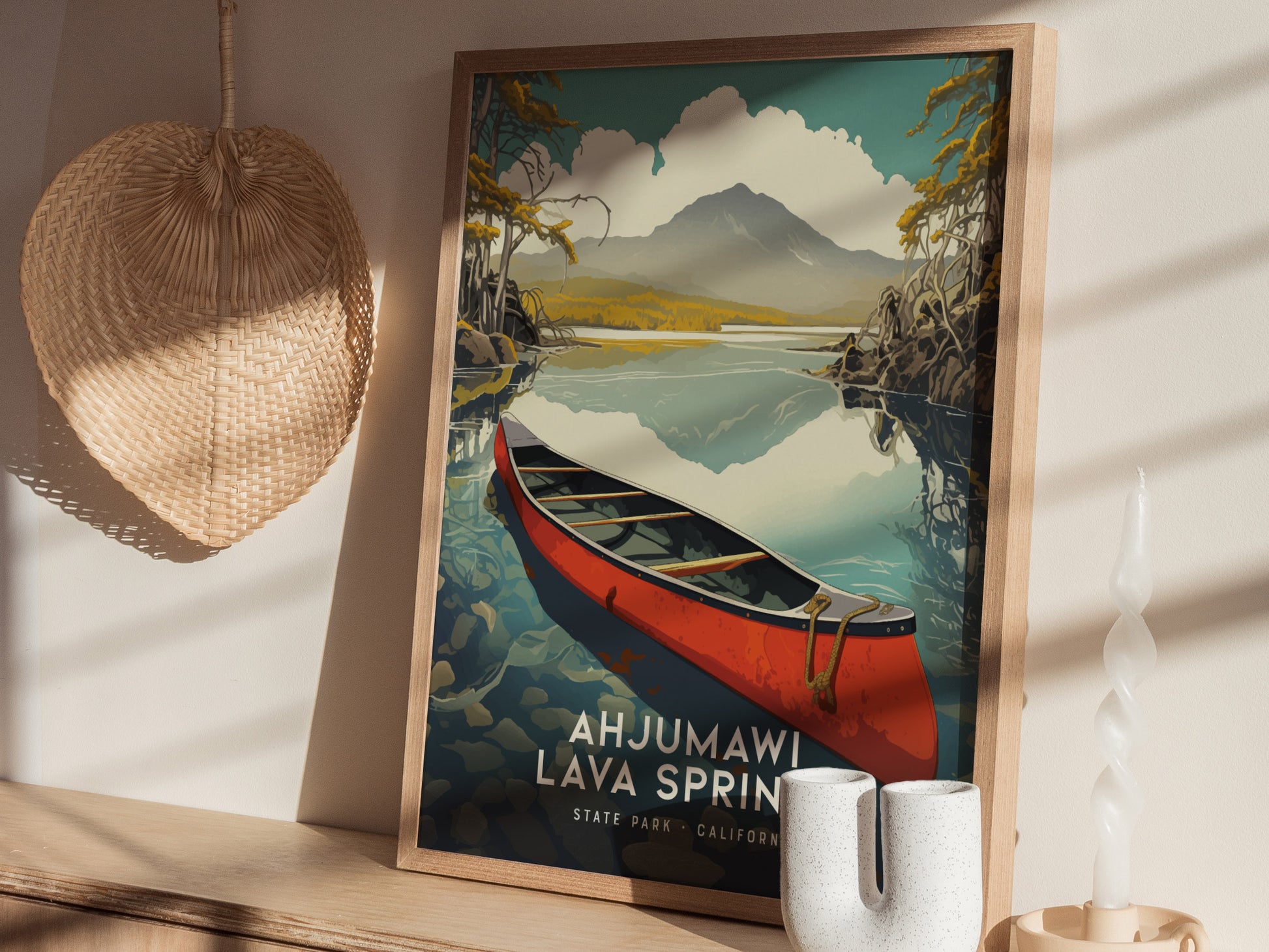 A framed poster of Ahjumawi Lava Springs features a red canoe on a serene lake with mountains in the background. It rests on a wooden shelf beside a woven basket.
