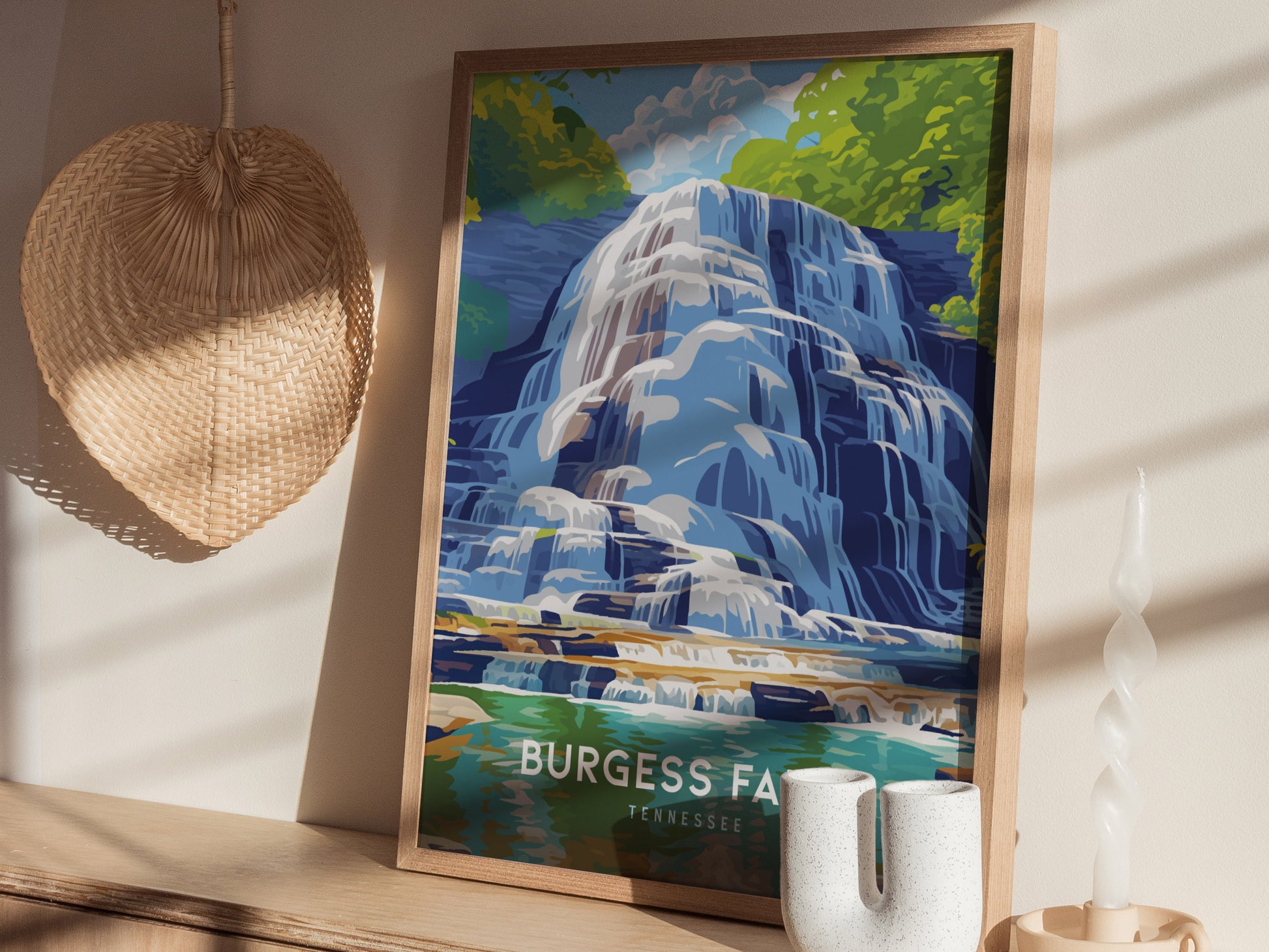 A framed poster of a waterfall with lush greenery, labeled Burgess Falls Tennessee, is displayed on a wooden shelf beside a wicker basket and decorative candle.