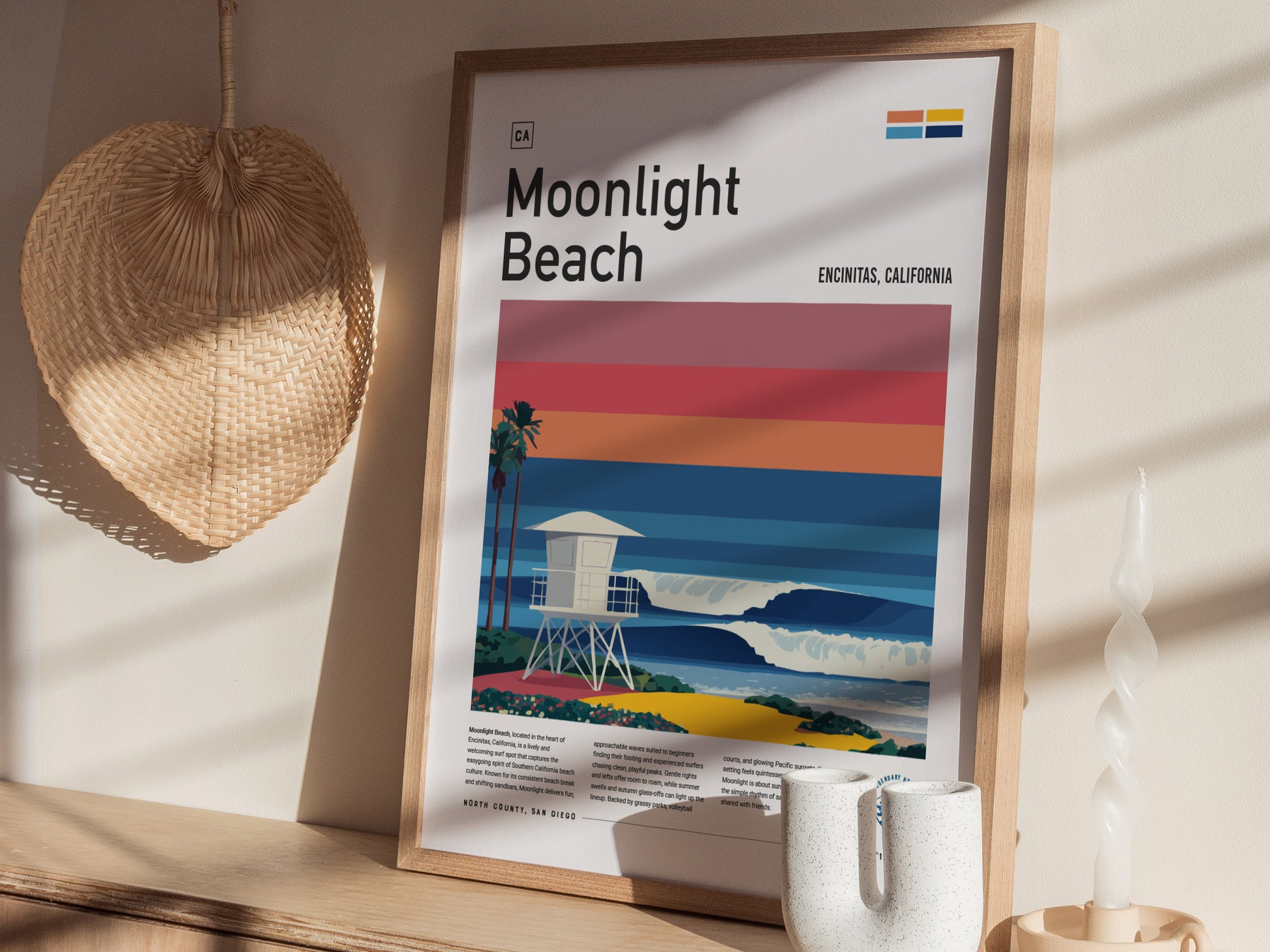 A framed art print titled Moonlight Beach showcases a stylized illustration of a lifeguard tower beside vibrant waves, set against a backdrop of layered sunset colors.