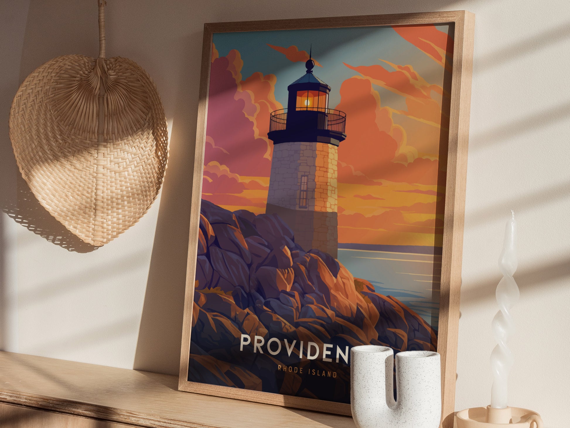 A framed poster of a lighthouse at sunset is placed on a wooden shelf, accompanied by a woven hat and decorative white candle. Shadows from window blinds are visible.