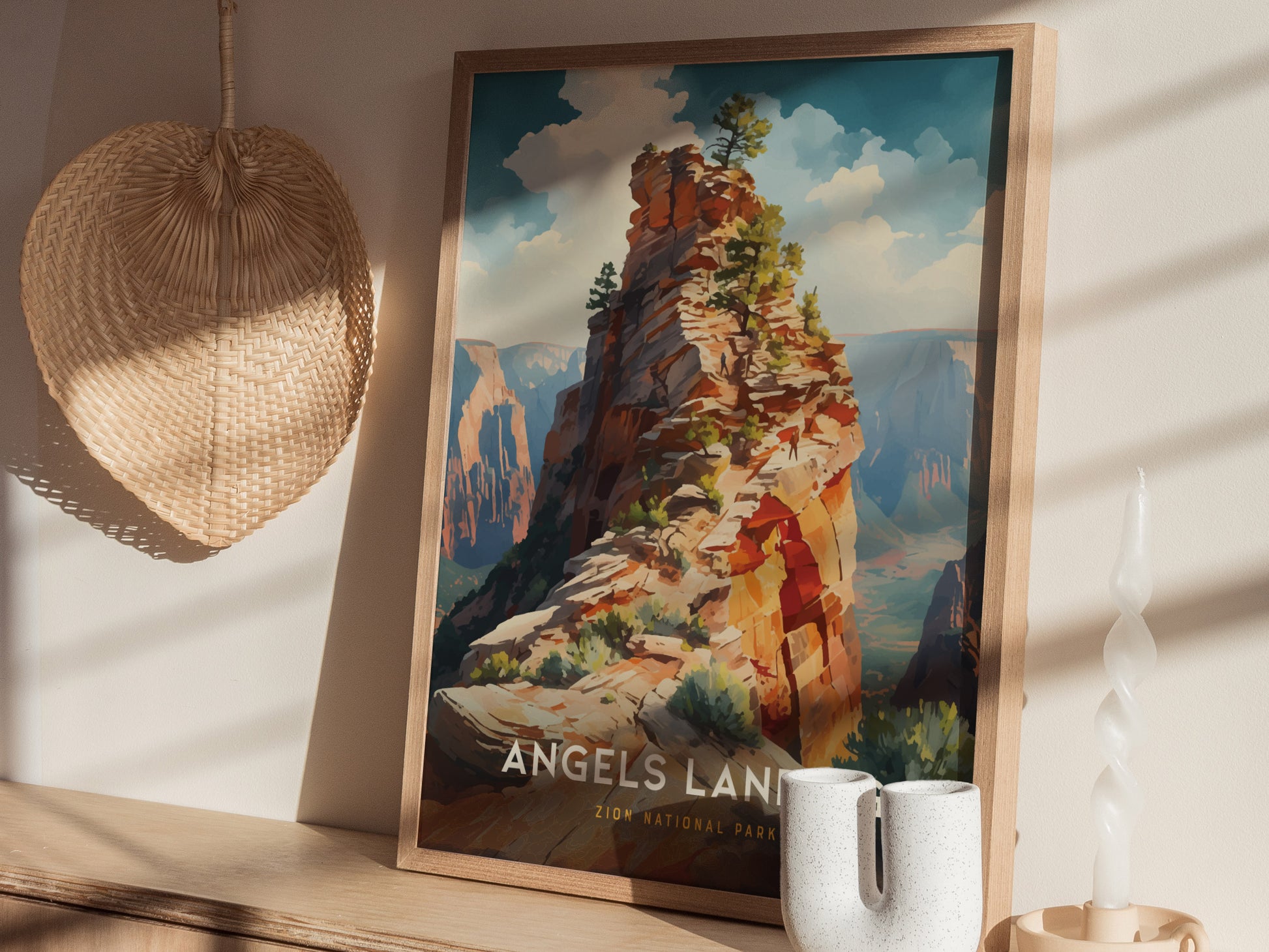 A framed poster of Angels Landing in Zion National Park is displayed on a wooden shelf alongside a woven wall hanging and a white decorative candle.
