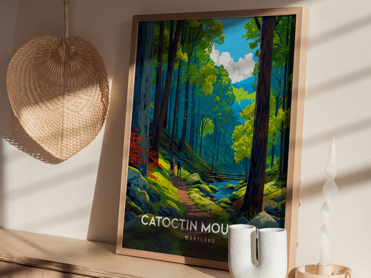A framed art print features a vibrant forest scene in Catoctin Mountain, Maryland, showcasing tall green trees, a winding stream, and a couple walking along a path.