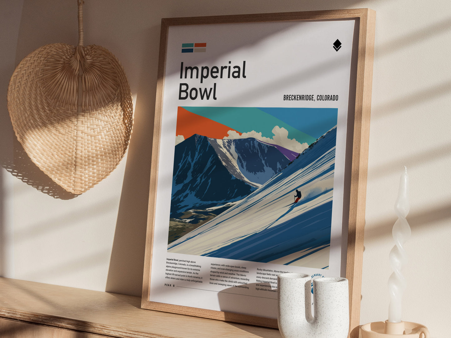A framed art print titled Imperial Bowl features a colorful illustration of a skier navigating a snowy slope with mountains in the background. The composition includes vibrant colors and geometric shapes, creating a dynamic winter scene.