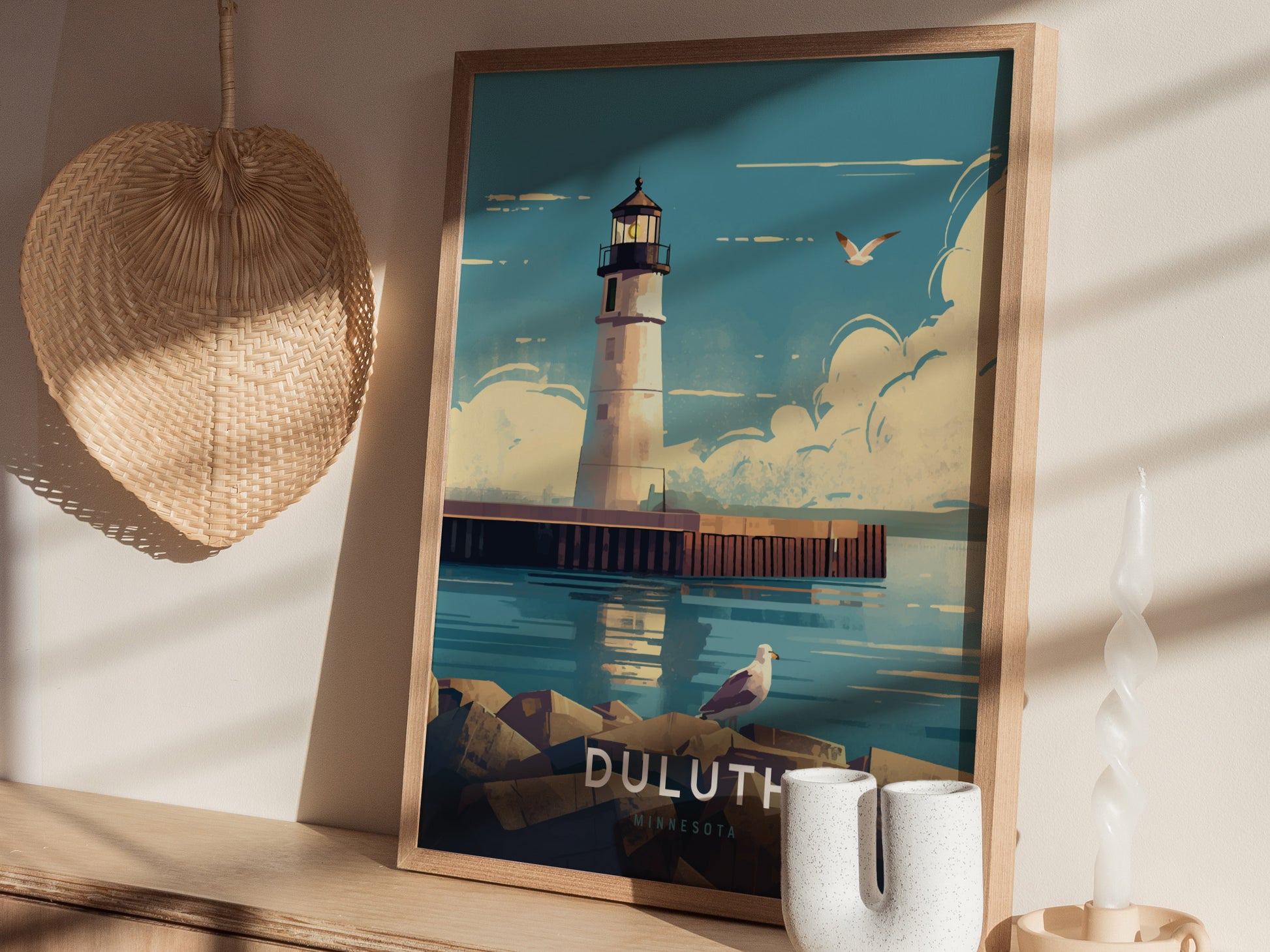 A framed illustration of the Duluth Harbor North Pier Lighthouse is displayed on a wooden shelf, accompanied by a woven basket and decorative candle, creating a serene coastal ambiance.