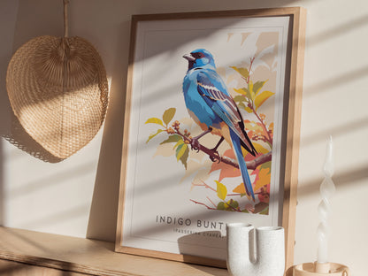 A framed art print of an indigo bunting bird perched on a branch, surrounded by autumn foliage. The bird is depicted in vibrant blues, while the background features warm hues, creating a striking contrast in a well-lit room setting.
