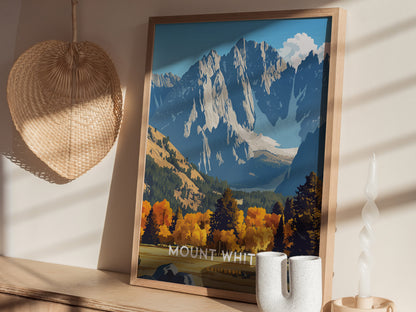 A framed poster of Mount Whitney with vibrant fall foliage and rugged peaks sits on a shelf beside a woven fan and a twisted candle.