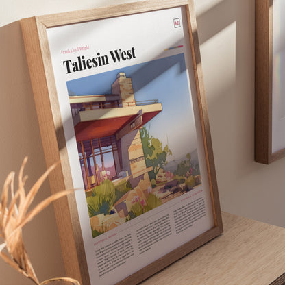 A framed poster of Taliesin West is displayed on a wooden surface, showcasing Frank Lloyd Wrights architectural design with desert plants and a modern structure.