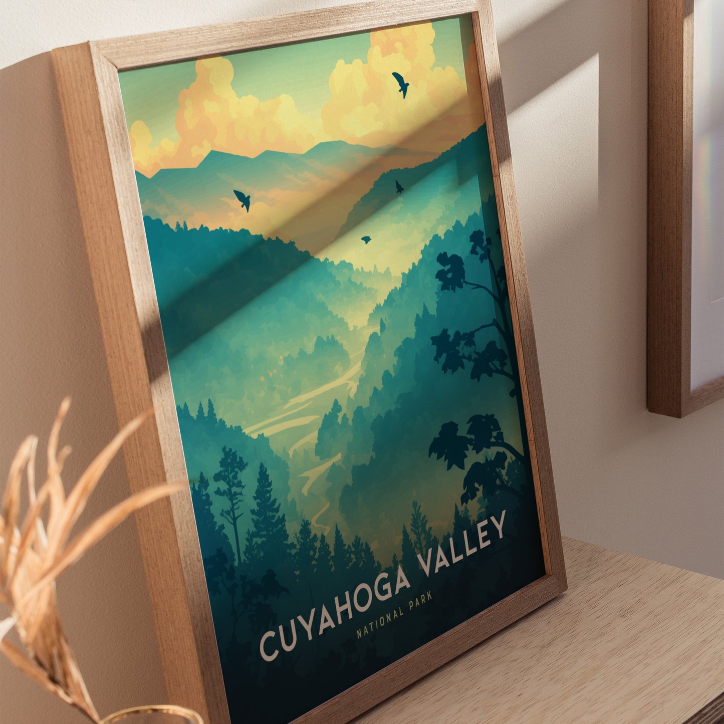 A framed poster of Cuyahoga Valley National Park featuring lush green hills, a winding river, and birds flying in a colorful sunset sky.