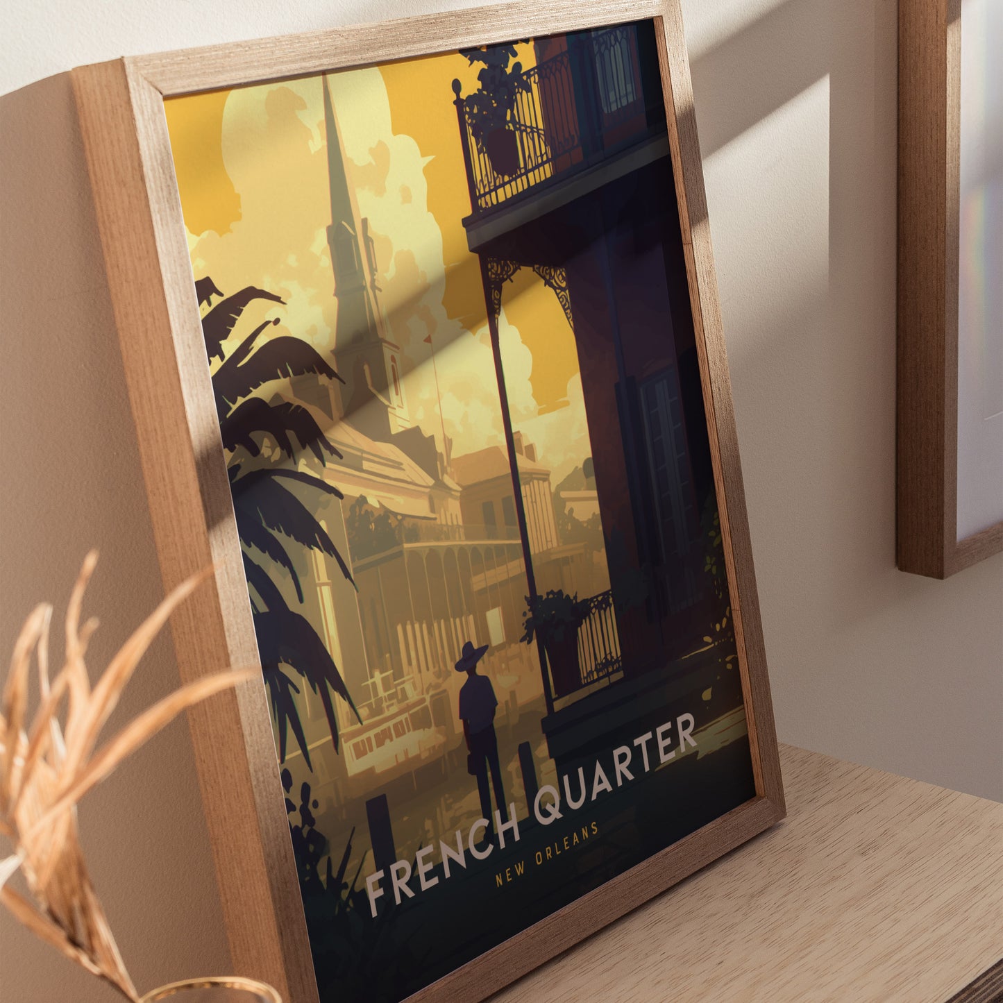 A framed poster depicting the French Quarter in New Orleans is displayed on a wooden surface, featuring a silhouette of a person against vibrant architecture under a warm, golden sky.