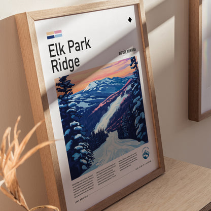 Framed poster of Elk Park Ridge features a colorful illustration of a snowy mountain landscape under a sunset sky. Displayed on a wooden surface with soft natural lighting.