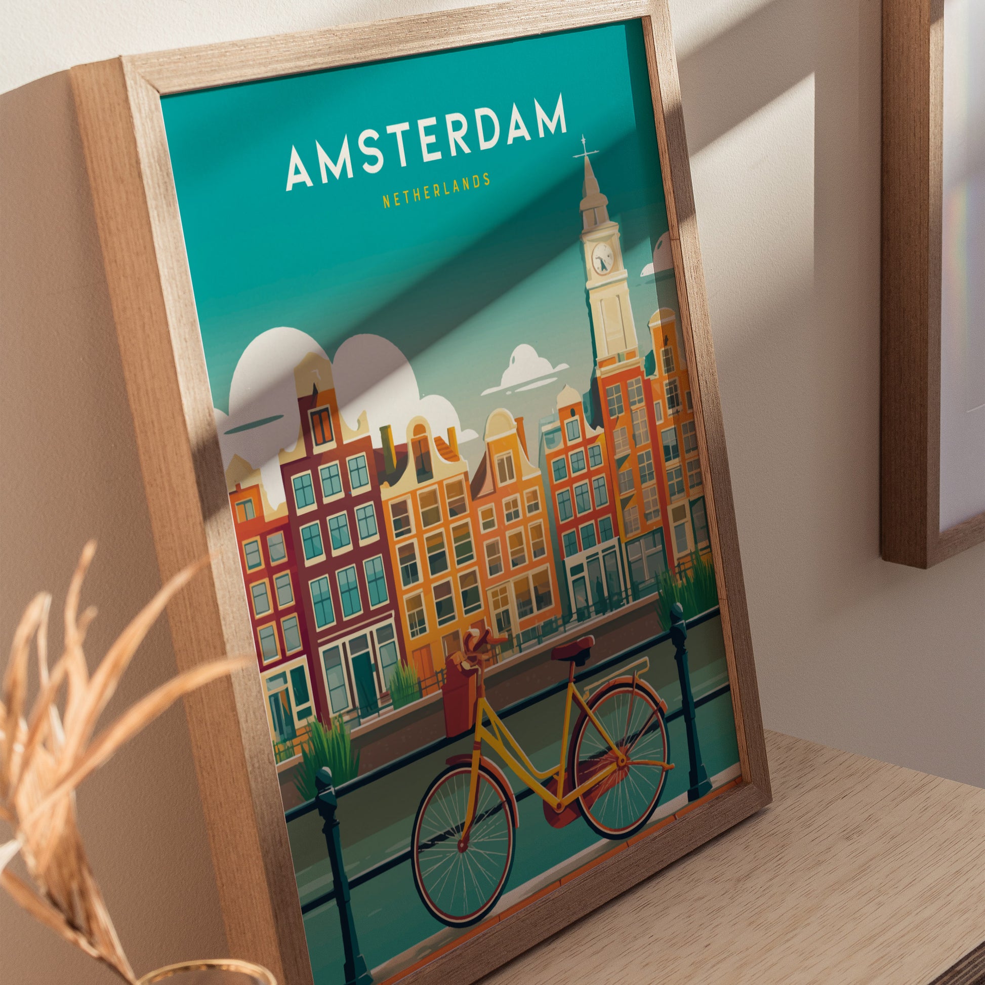 A framed poster featuring a vibrant illustration of Amsterdams iconic canal houses in warm colors, with a yellow bicycle parked by the water. The background includes a clear sky and a clock tower, adding to the charm of the scene.