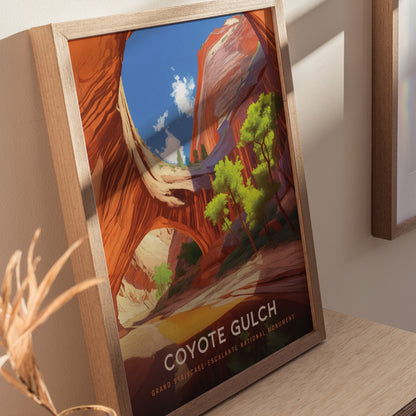 Framed artwork depicting Coyote Gulch features vibrant red sandstone arches and lush green trees under a clear blue sky. The poster is displayed on a light wooden shelf.