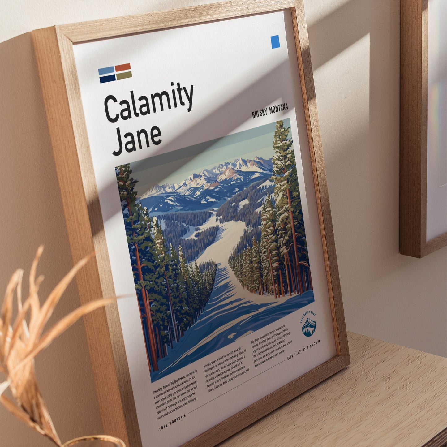Framed poster titled Calamity Jane featuring a ski run through snow-covered pines at Big Sky, Montana. Sunlight casts shadows on the wooden frame and surrounding wall.