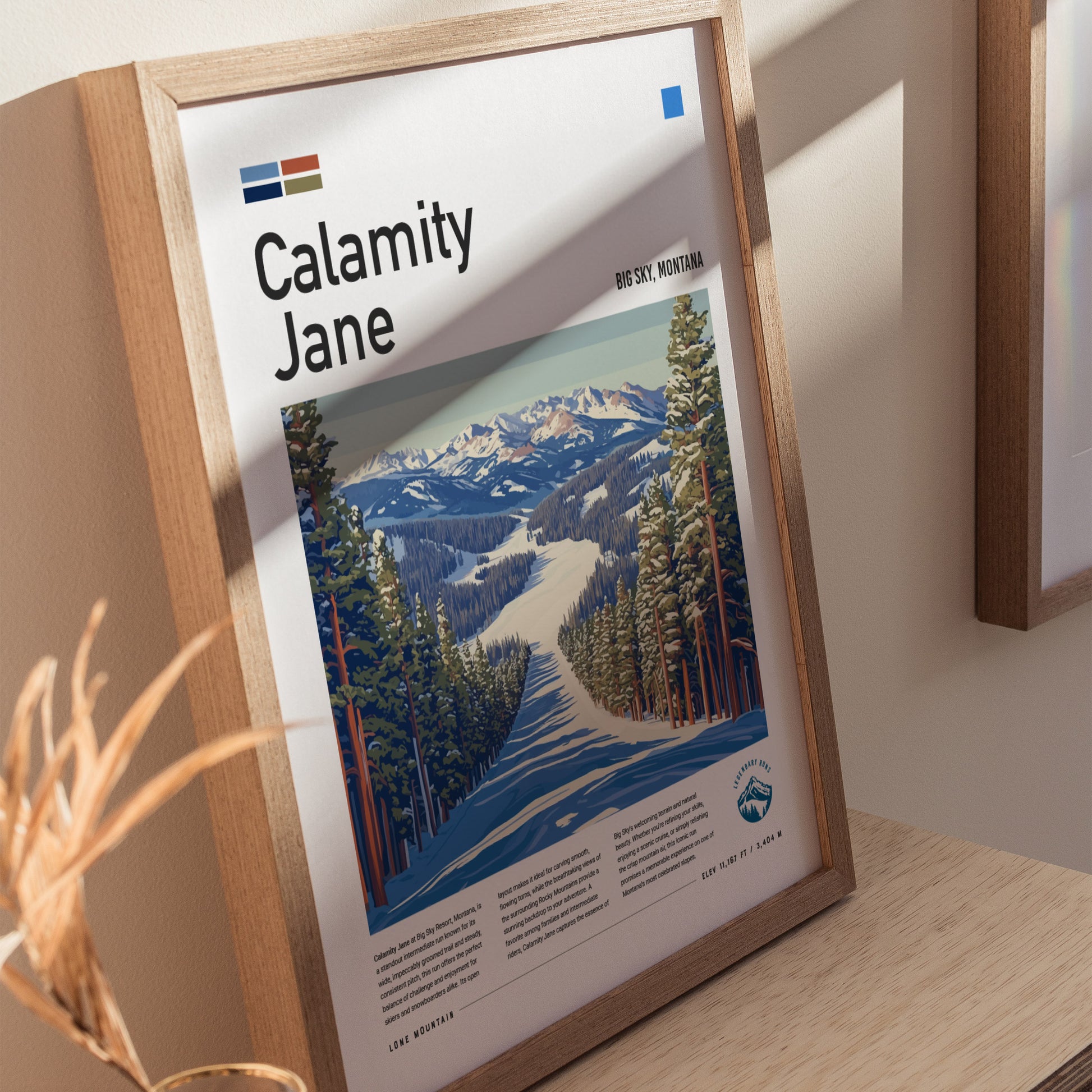 Framed poster titled Calamity Jane featuring a ski run through snow-covered pines at Big Sky, Montana. Sunlight casts shadows on the wooden frame and surrounding wall.