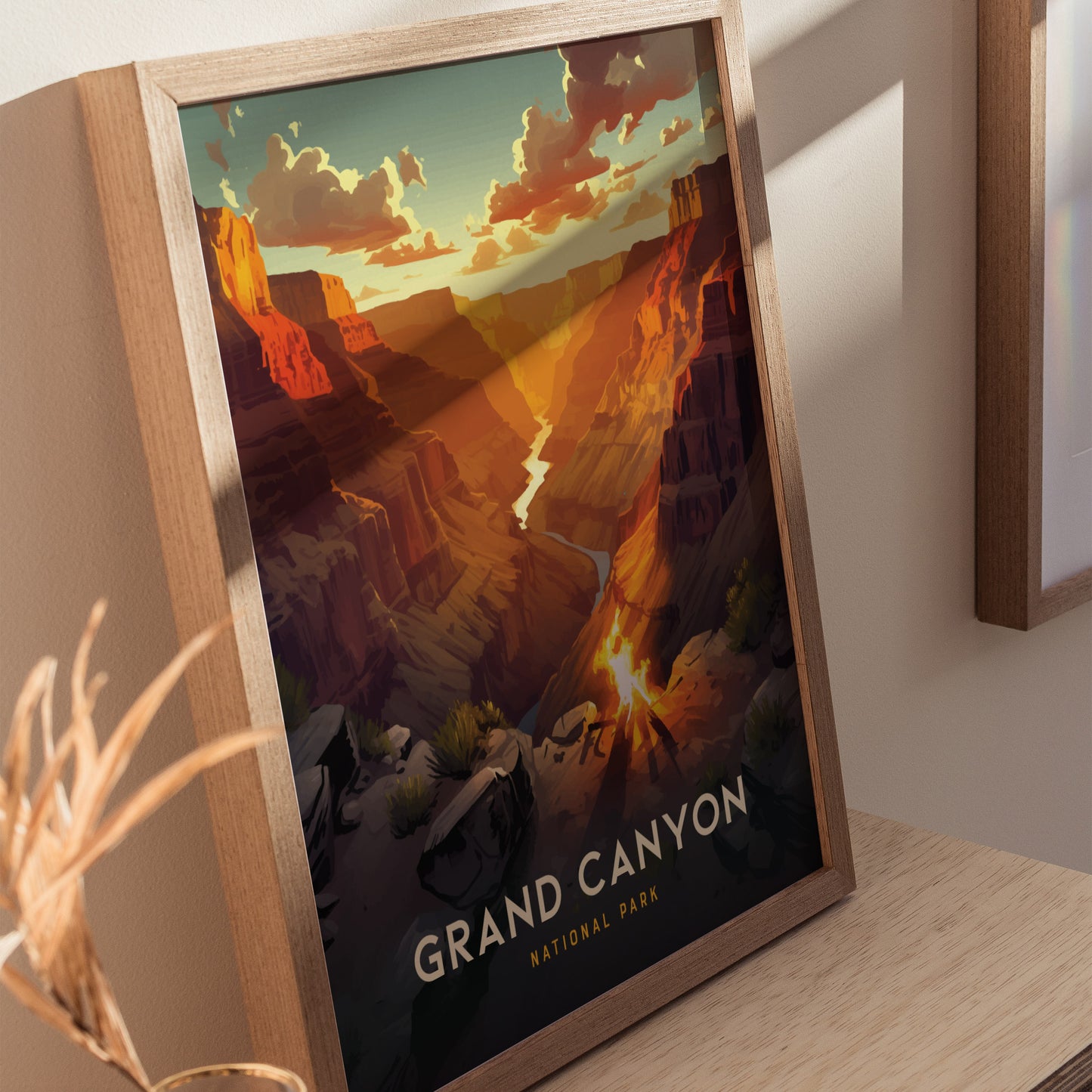 A framed poster depicting the Grand Canyon with vibrant sunset hues illuminating the canyon walls, showcasing dramatic shadows and a winding river.