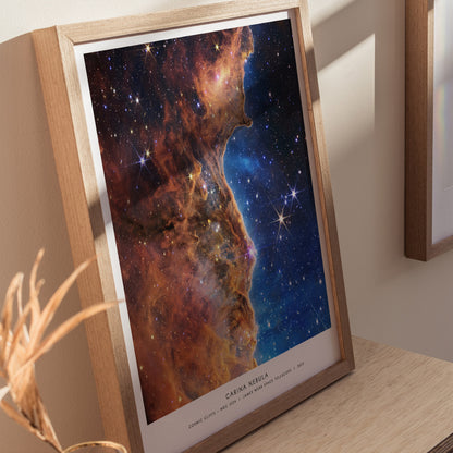 Wood frame Carina Nebula JWST print styled on a shelf with soft lighting