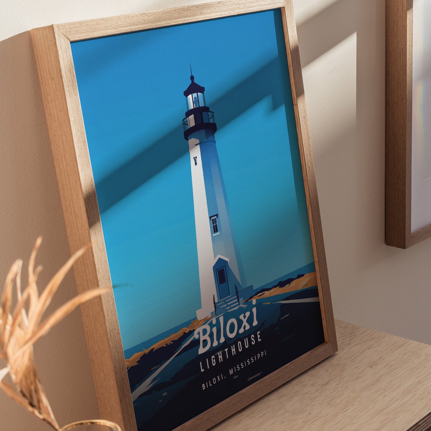Framed poster of the Biloxi Lighthouse with a bold, minimal design, featuring a blue sky and coastal landscape. The words Biloxi Lighthouse, Biloxi, Mississippi are visible at the bottom.
