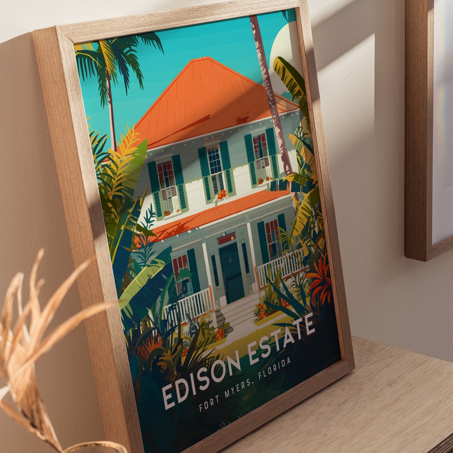 Framed poster depicting the Thomas Edison Estate in Fort Myers, Florida, featuring a white house with a red roof, surrounded by lush tropical plants and palm trees.
