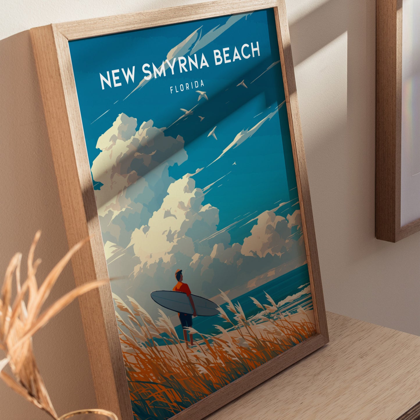 Framed poster featuring a surfer with a board, standing on a beach with tall grass, under a sky filled with dramatic clouds. Text reads New Smyrna Beach, Florida.