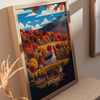 A framed poster depicting a white church steeple surrounded by vibrant autumn foliage in shades of orange, red, and gold, with mountains and a blue sky in the background.