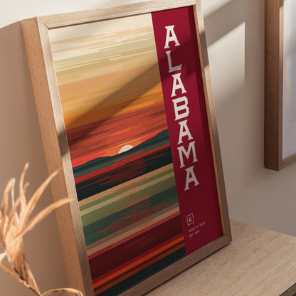 A framed poster with abstract horizontal lines in warm colors, featuring the word Alabama in bold letters on the right. The design includes a stylized sunset and landscape.