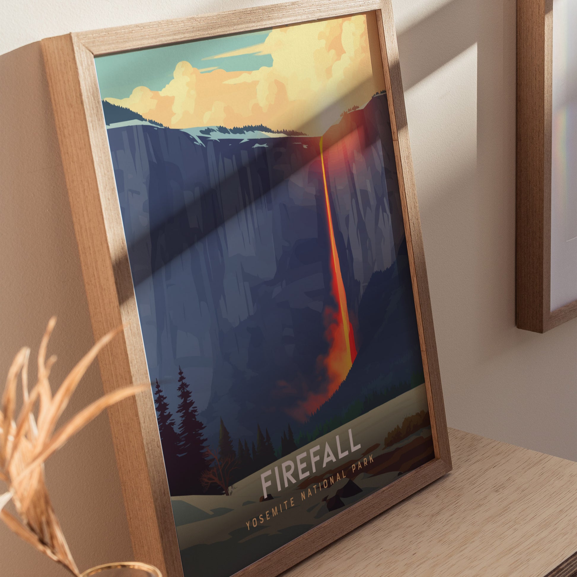 Framed artwork of a waterfall titled 'Firefall' by Yosemite National Park on a wooden surface.
